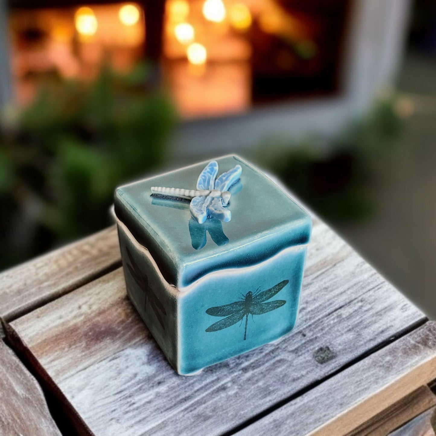 Deep green ceramic container with dragonfly design on a wooden surface