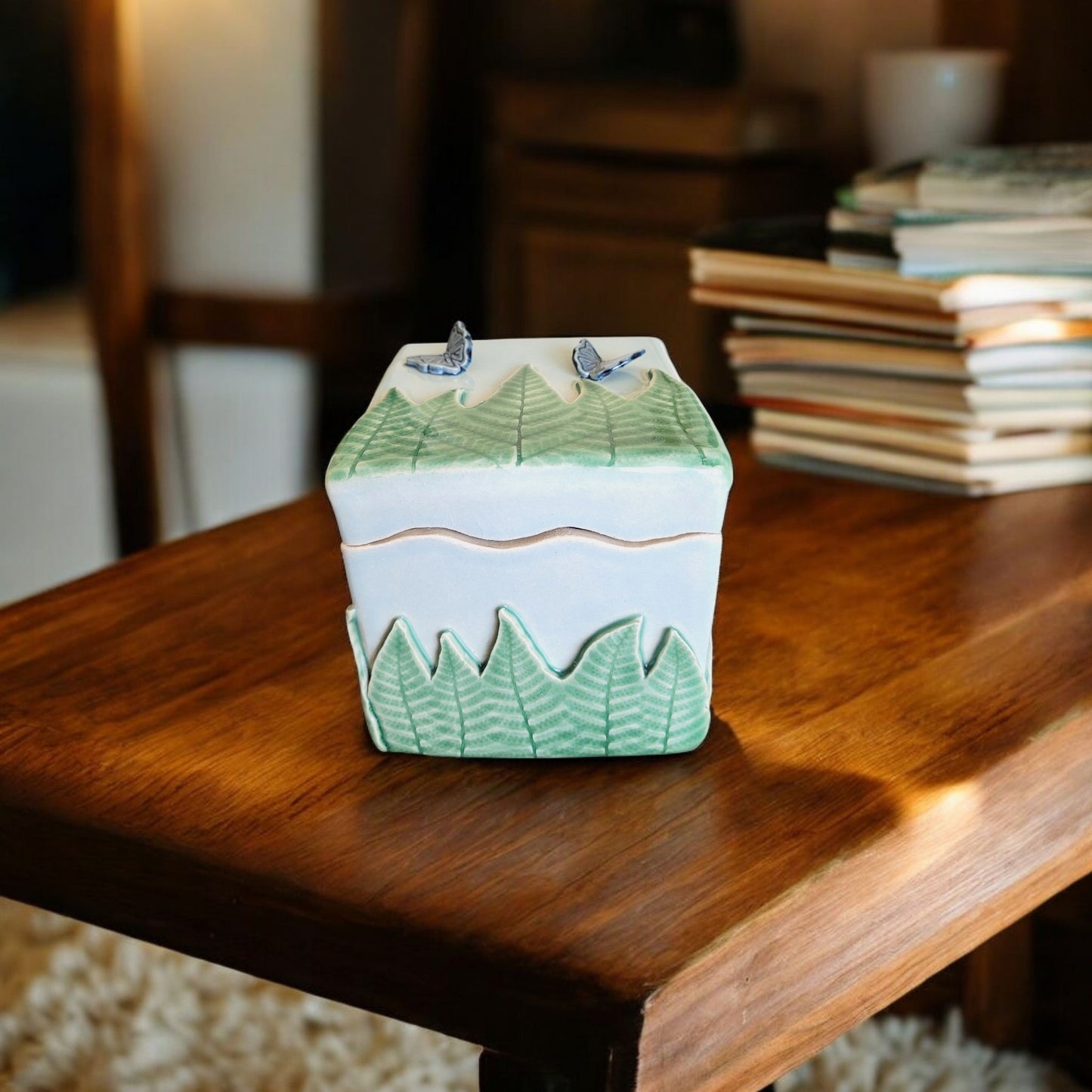 Ceramic container with green ferns on a wooden surface