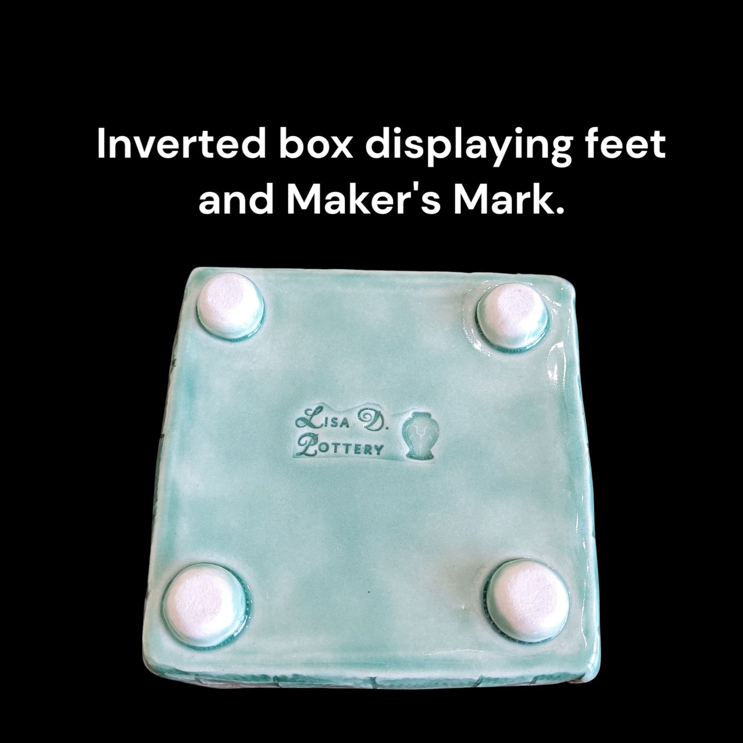 Inverted box with feet and 'Lisa D Pottery' maker's mark on a black background
