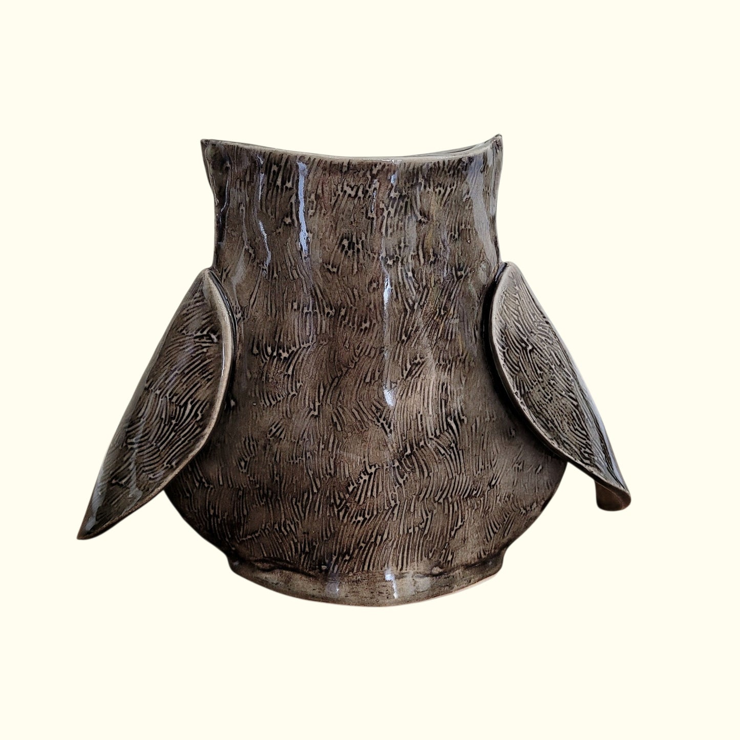 Rear view of decorative owl-shaped vase with textured surface on a white background