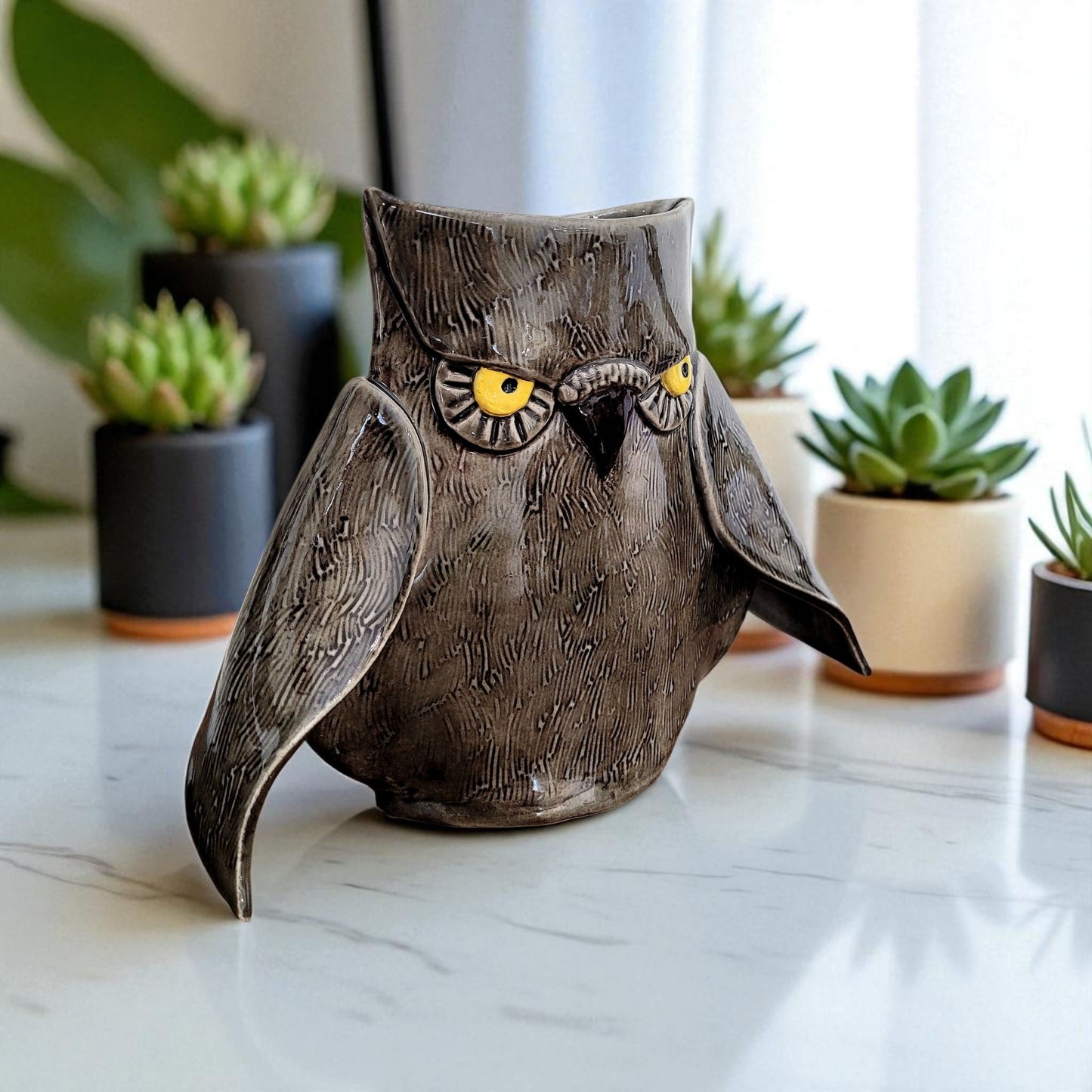 Decorative owl vase on a marble surface with potted plants in the background