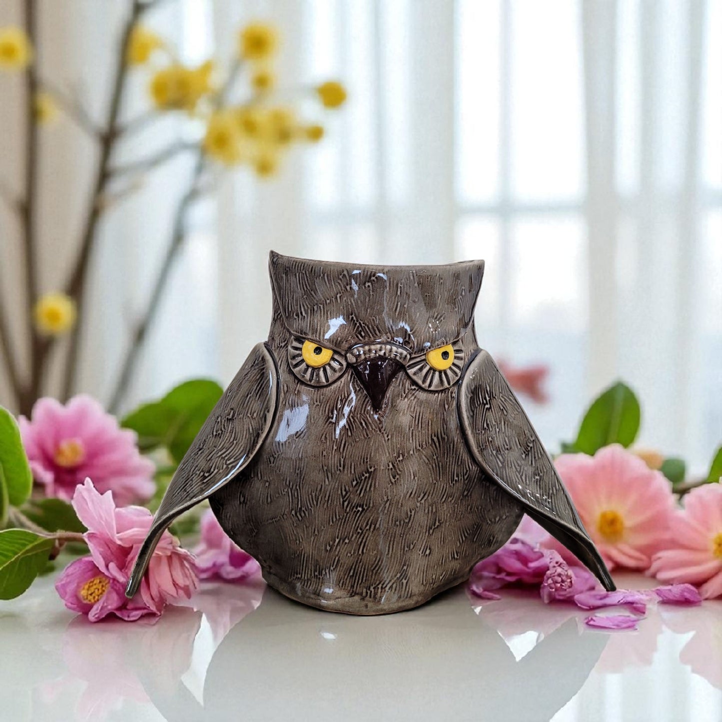 Decorative owl vase with flowers in the background