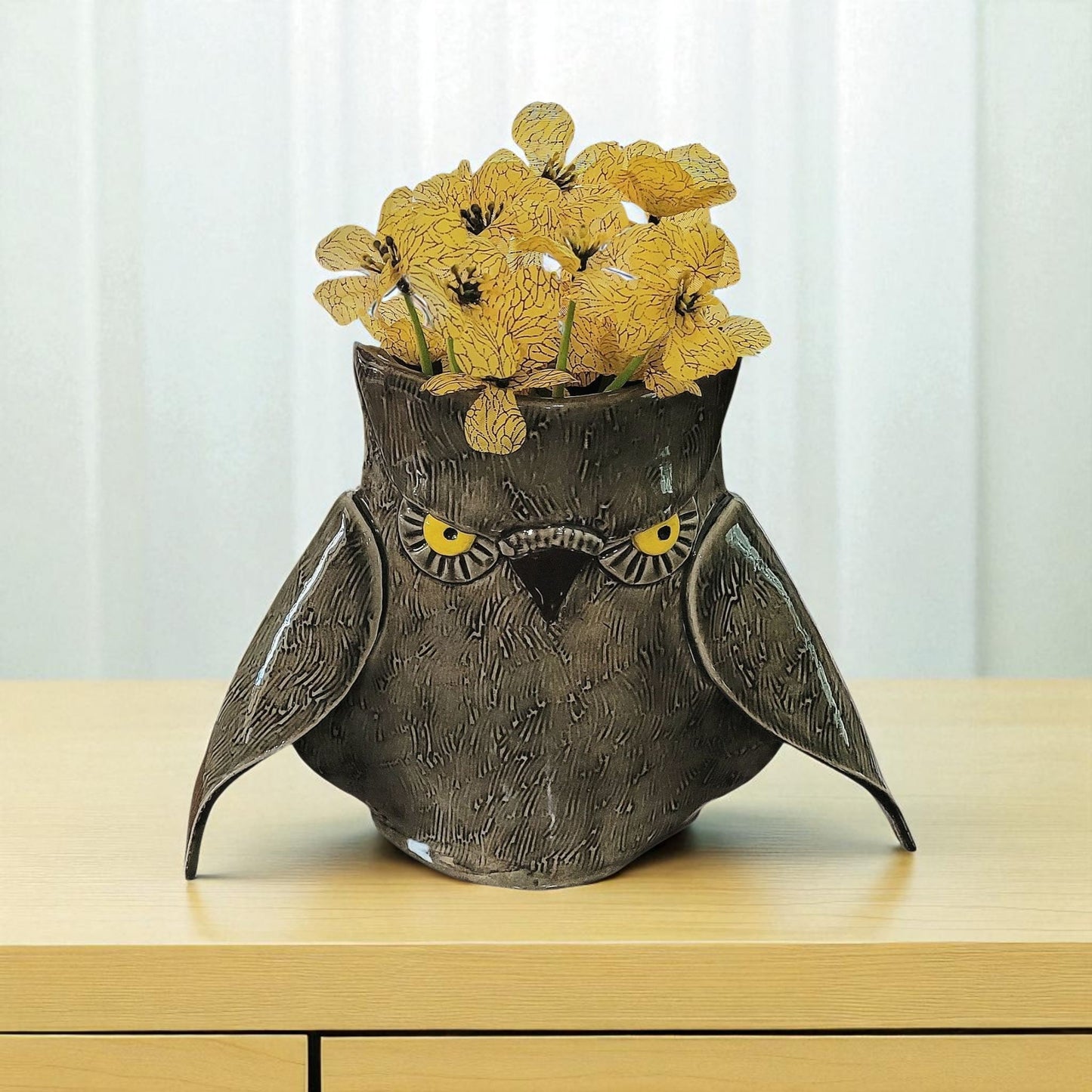 Owl-shaped vase with yellow flowers on a wooden surface