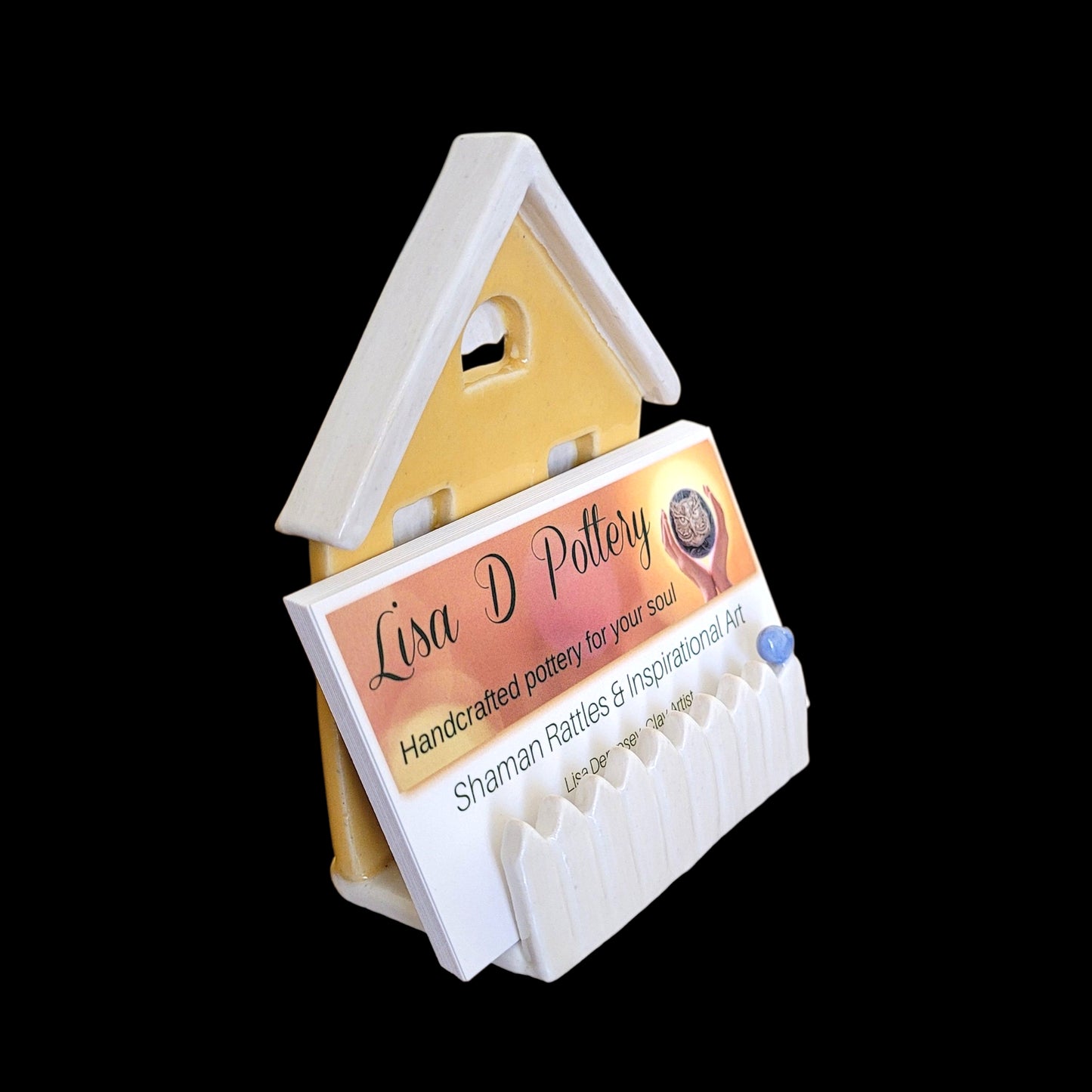 House-shaped card holder with a business card featuring 'Lisa D Pottery' on a white background