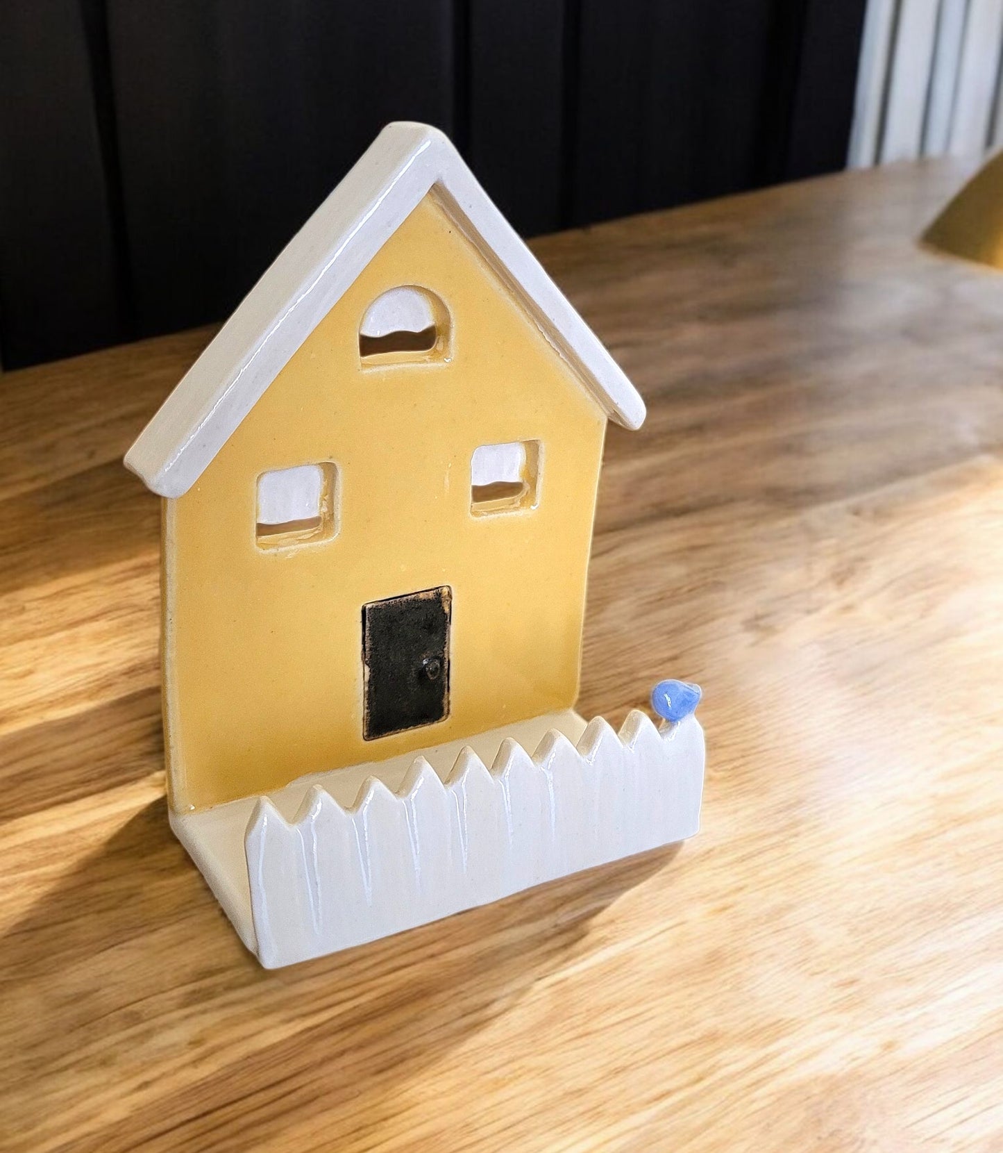 Yellow house-shaped business card holder on a wooden surface