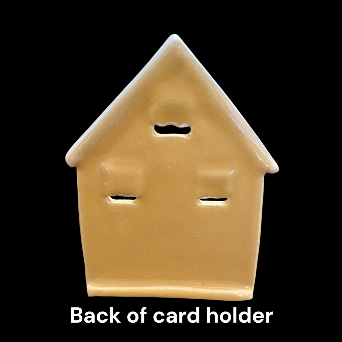 Back of ceramic card holder shaped like a house on a black background