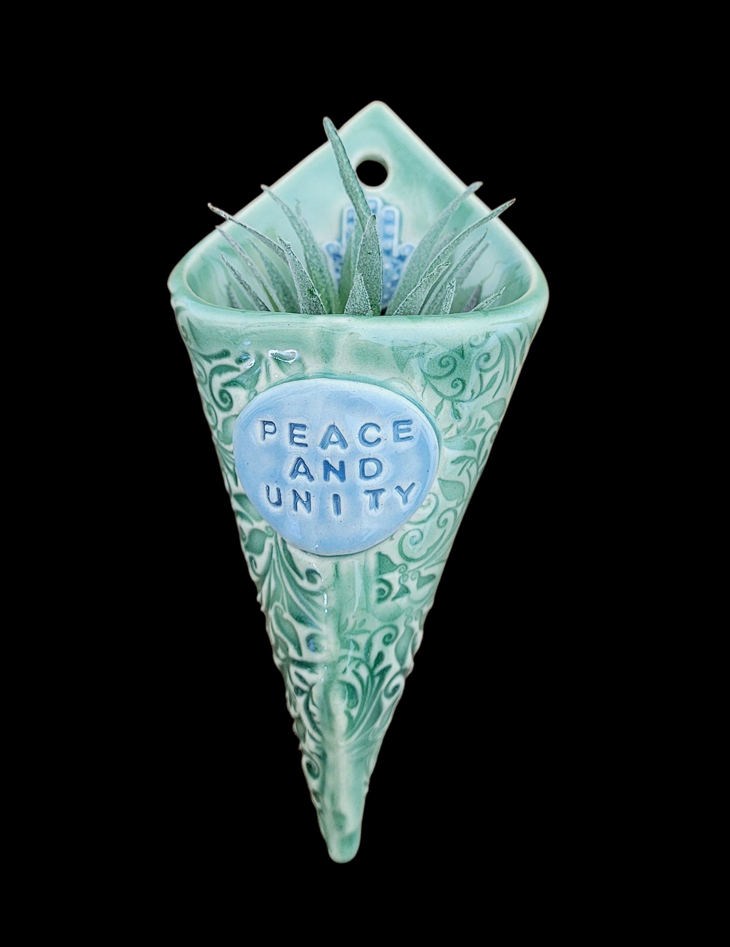 Decorative wall hanging with 'Peace and Unity' text on a black background