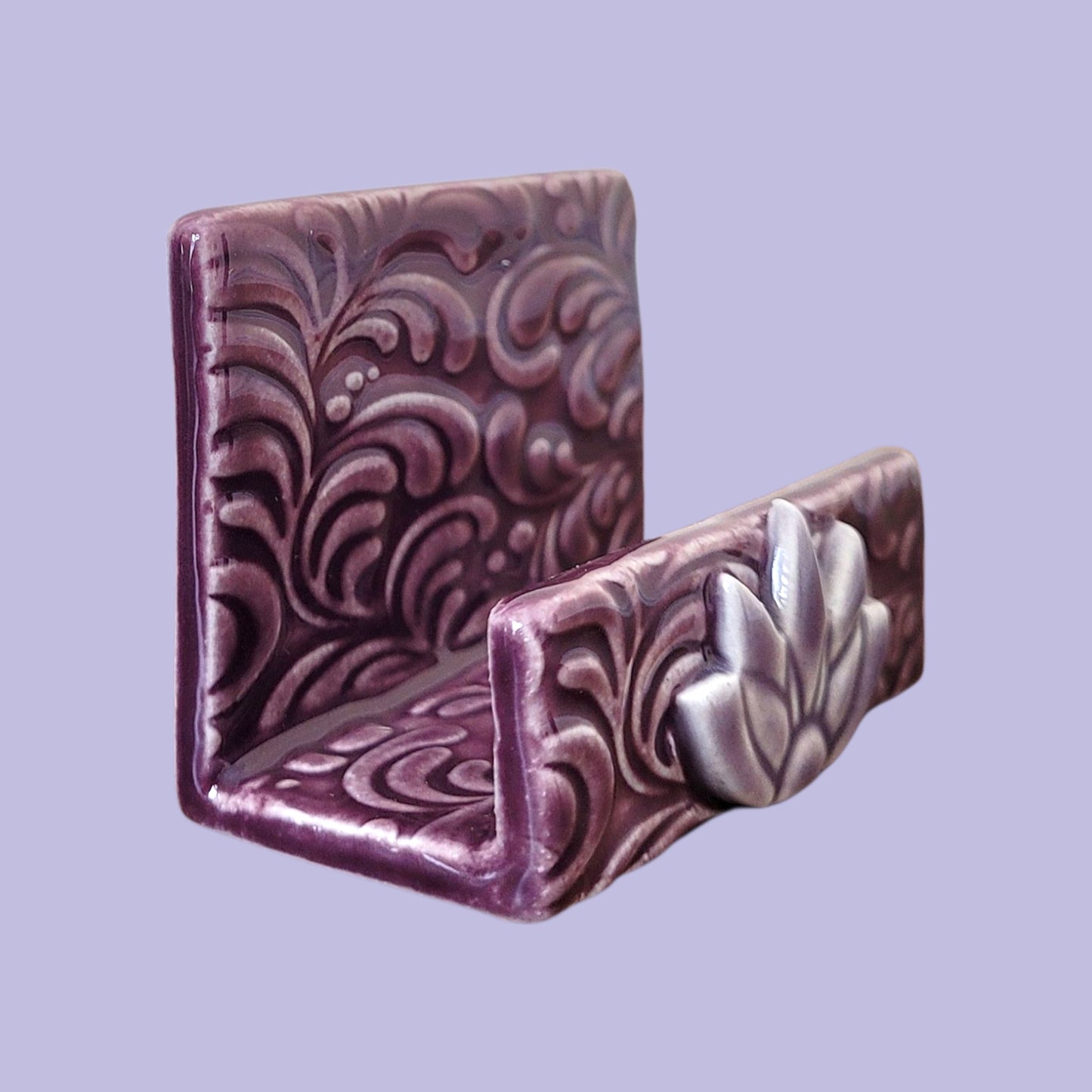 Purple and lavender business card holder with scroll patterns on a light purple background