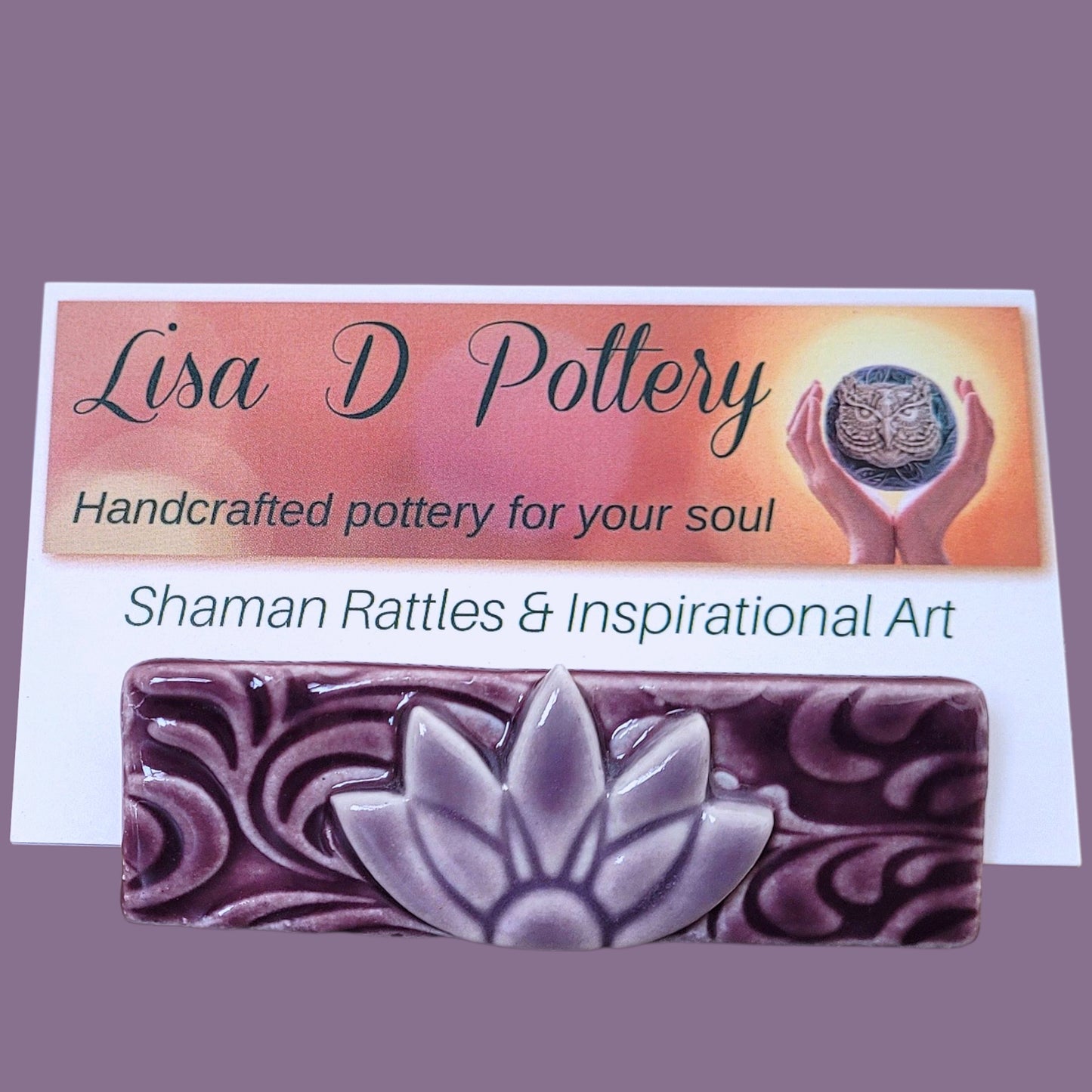 Card with 'Lisa D Pottery' branding sitting in a purple and lavender business card holder.