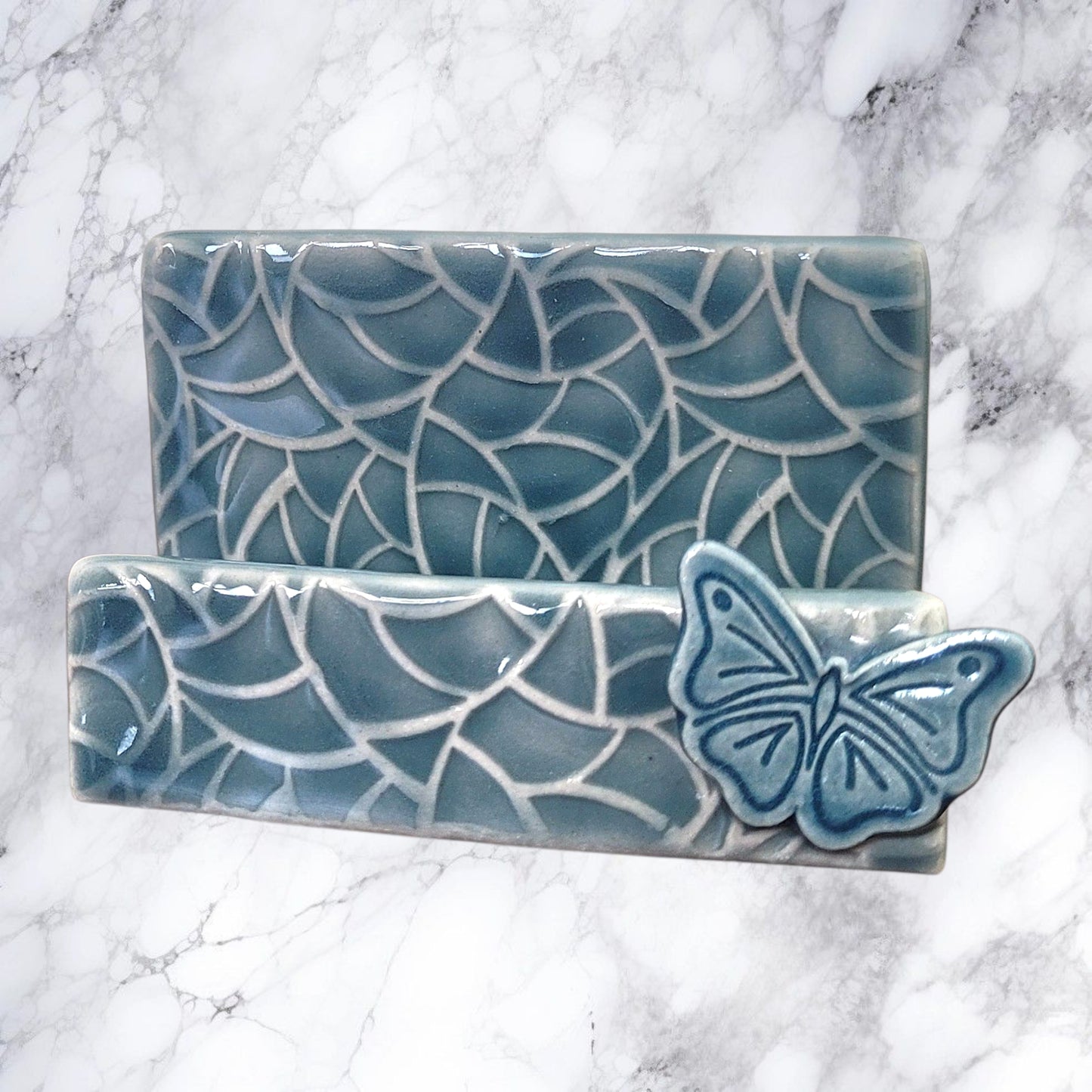 Ceramic business card holder with butterfly design on a marble background