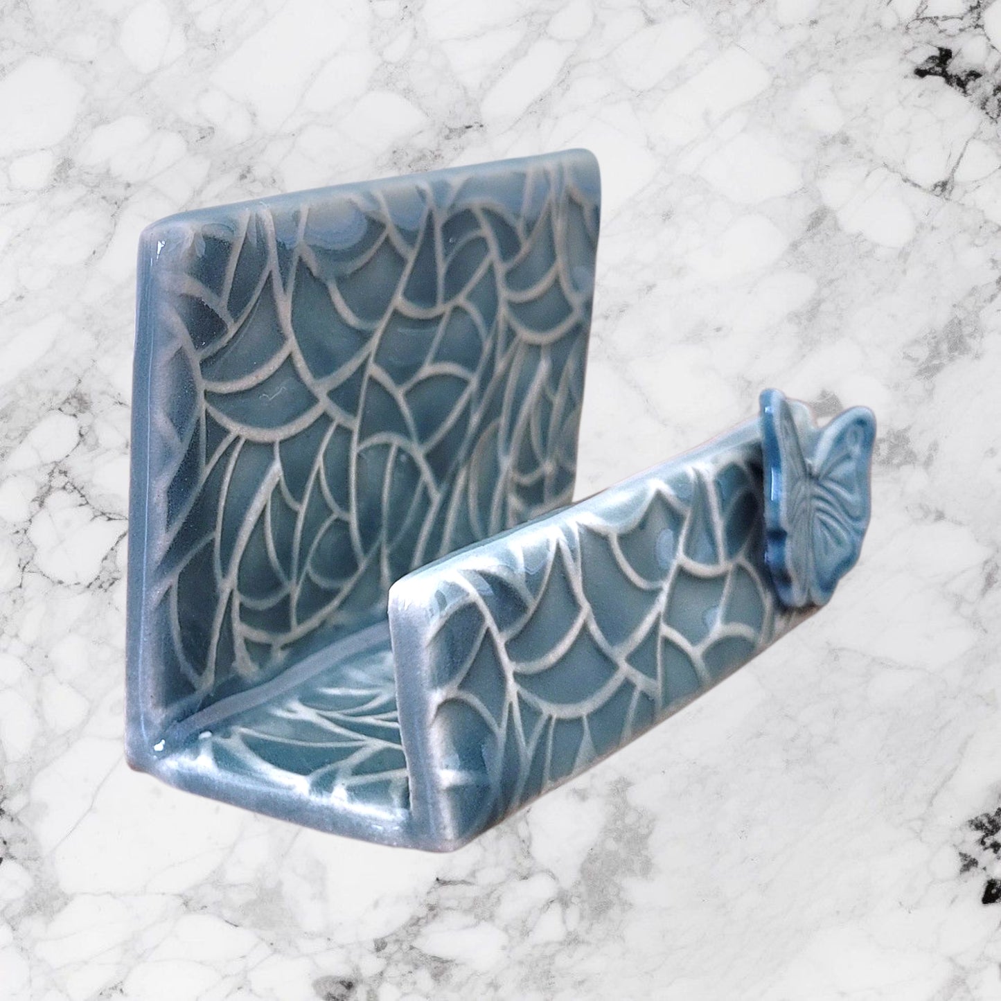Blue business card holder with butterfly on a marble background