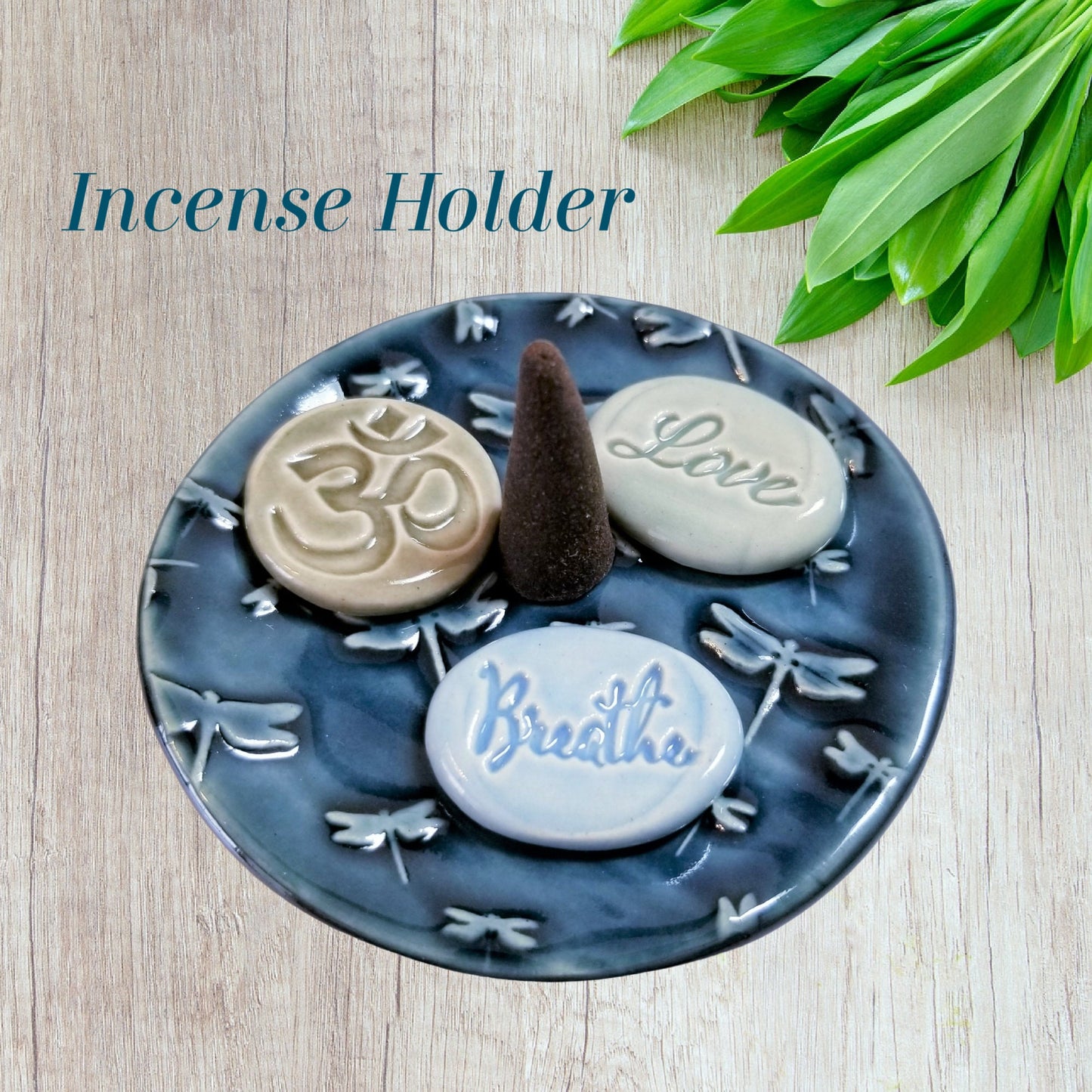 Stoneware dragonfly dish holding meditation stones and incense cone on wooden surface"