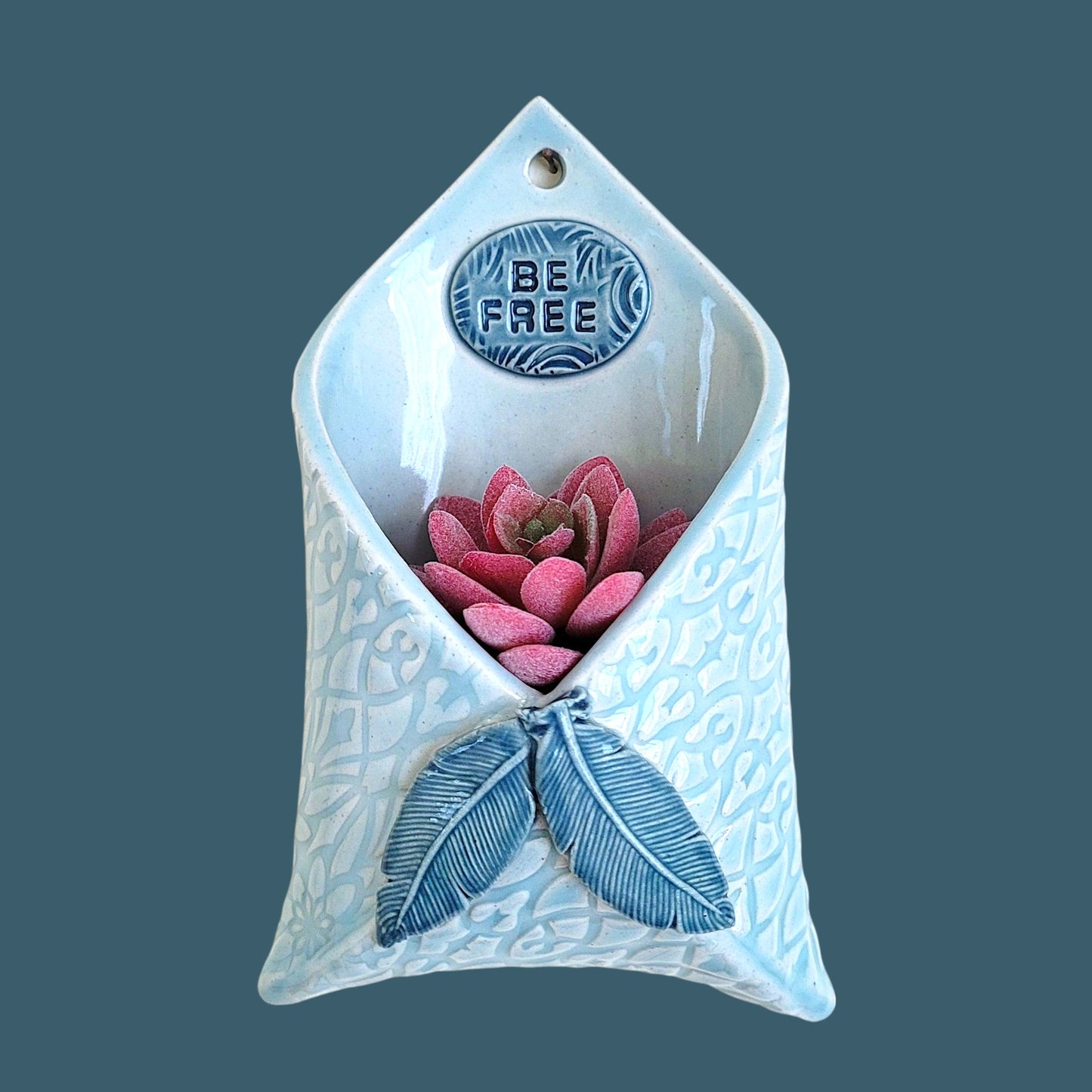 Handcrafted stoneware wall pocket featuring natural feather design with 'Be Free' inspirational message, glazed ceramic art piece for home decor