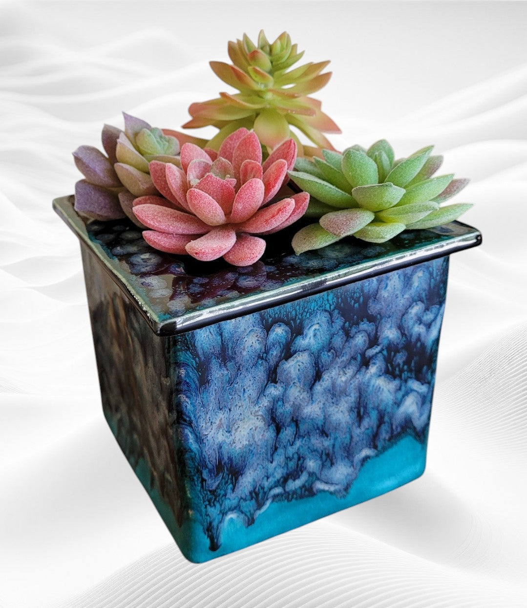 Handcrafted stoneware planter with colorful succulents on a white background