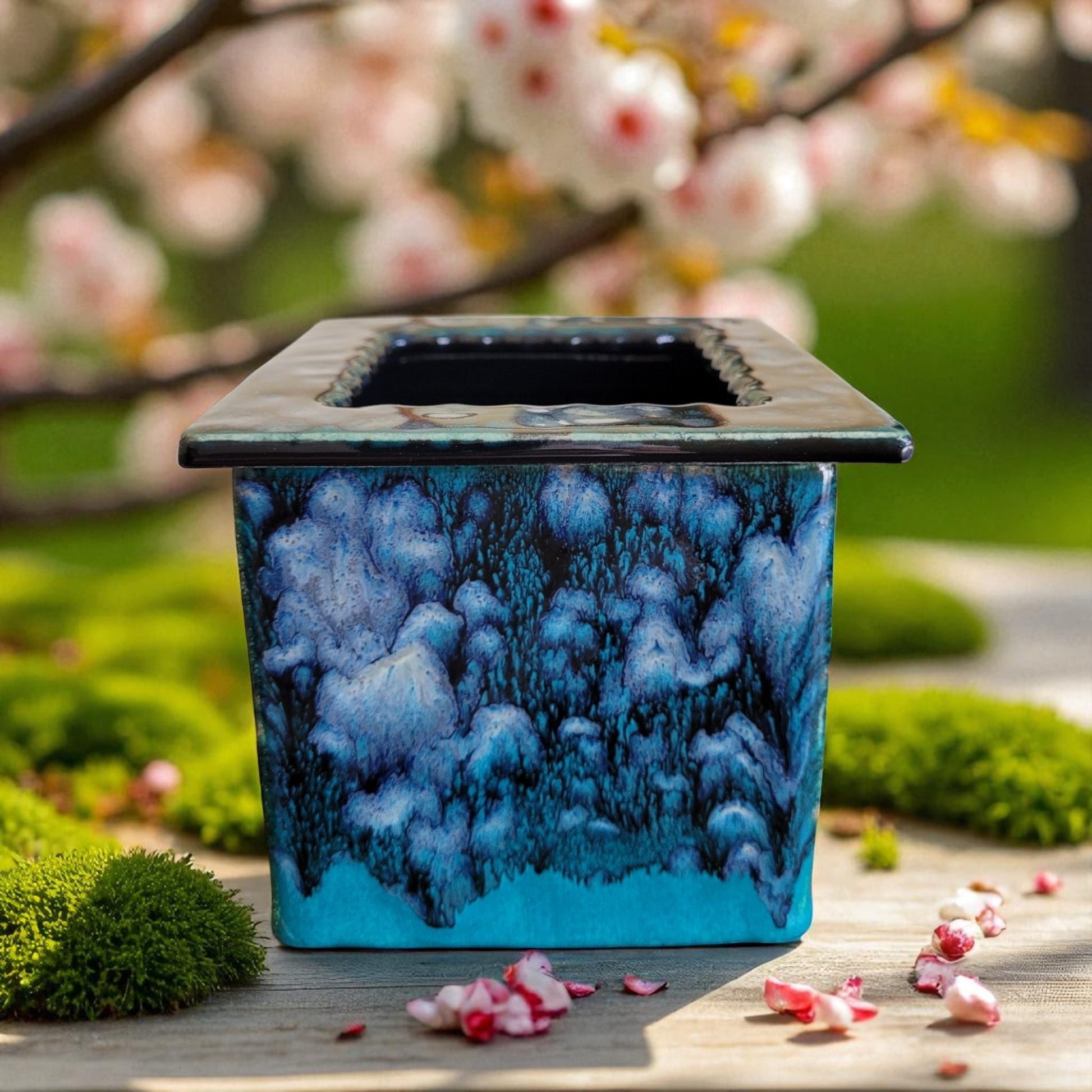 Blue ceramic planter with a marbled design in a garden setting with cherry blossoms.