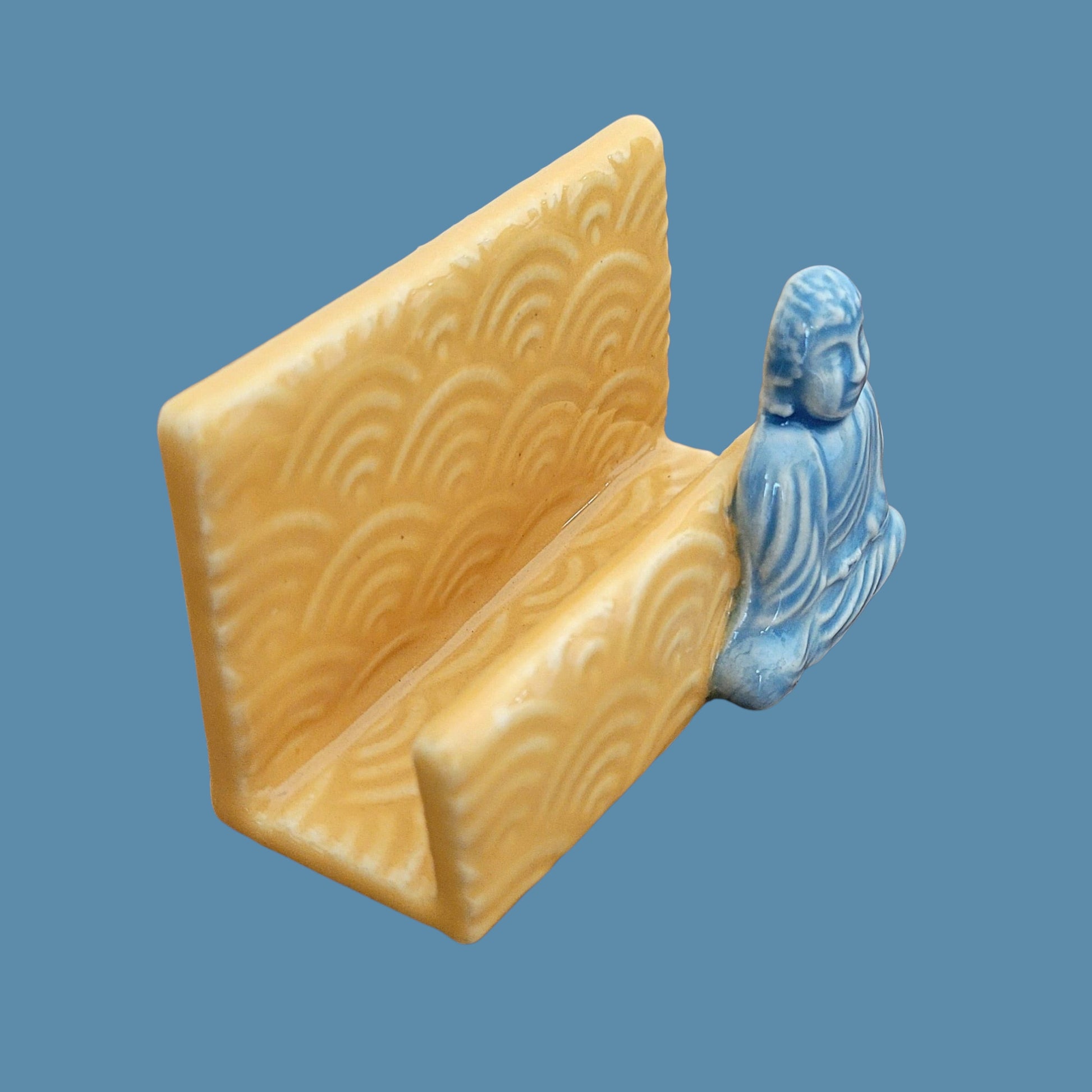 Yellow business card holder with blue Buddha figure on a blue background