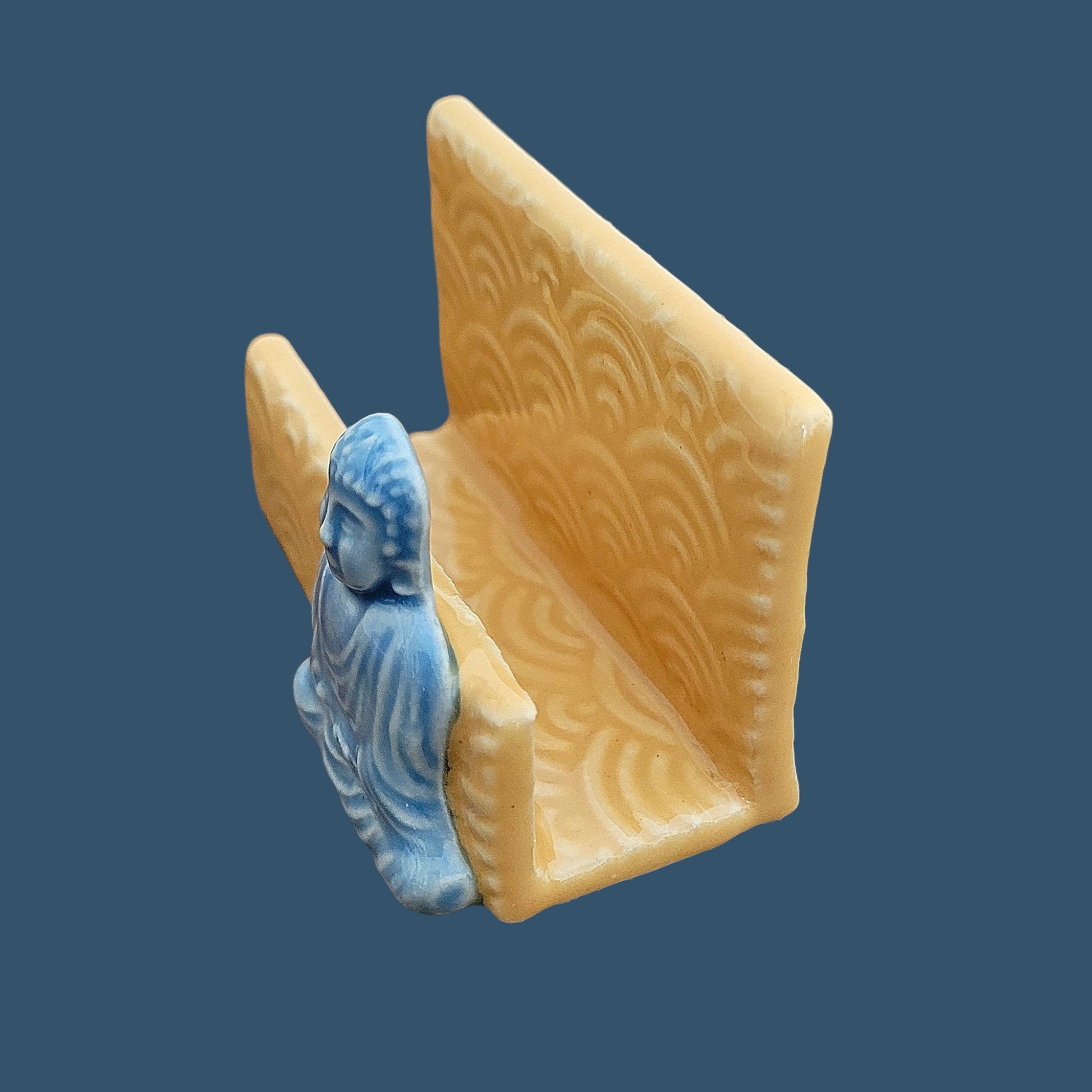 side view of a buddha business card holder on a blue background