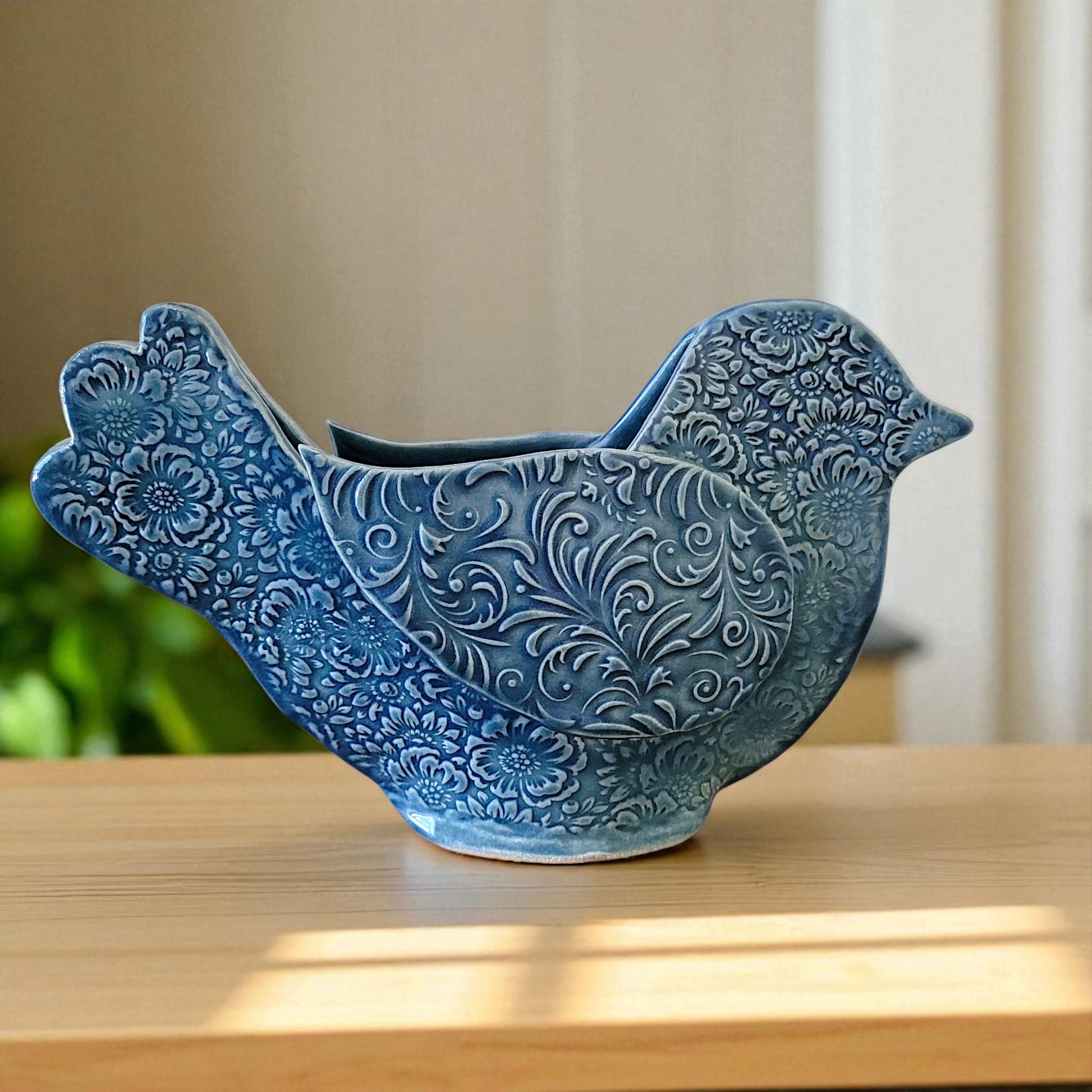 Blue ceramic bird-shaped vase on a wooden surface with a blurred background