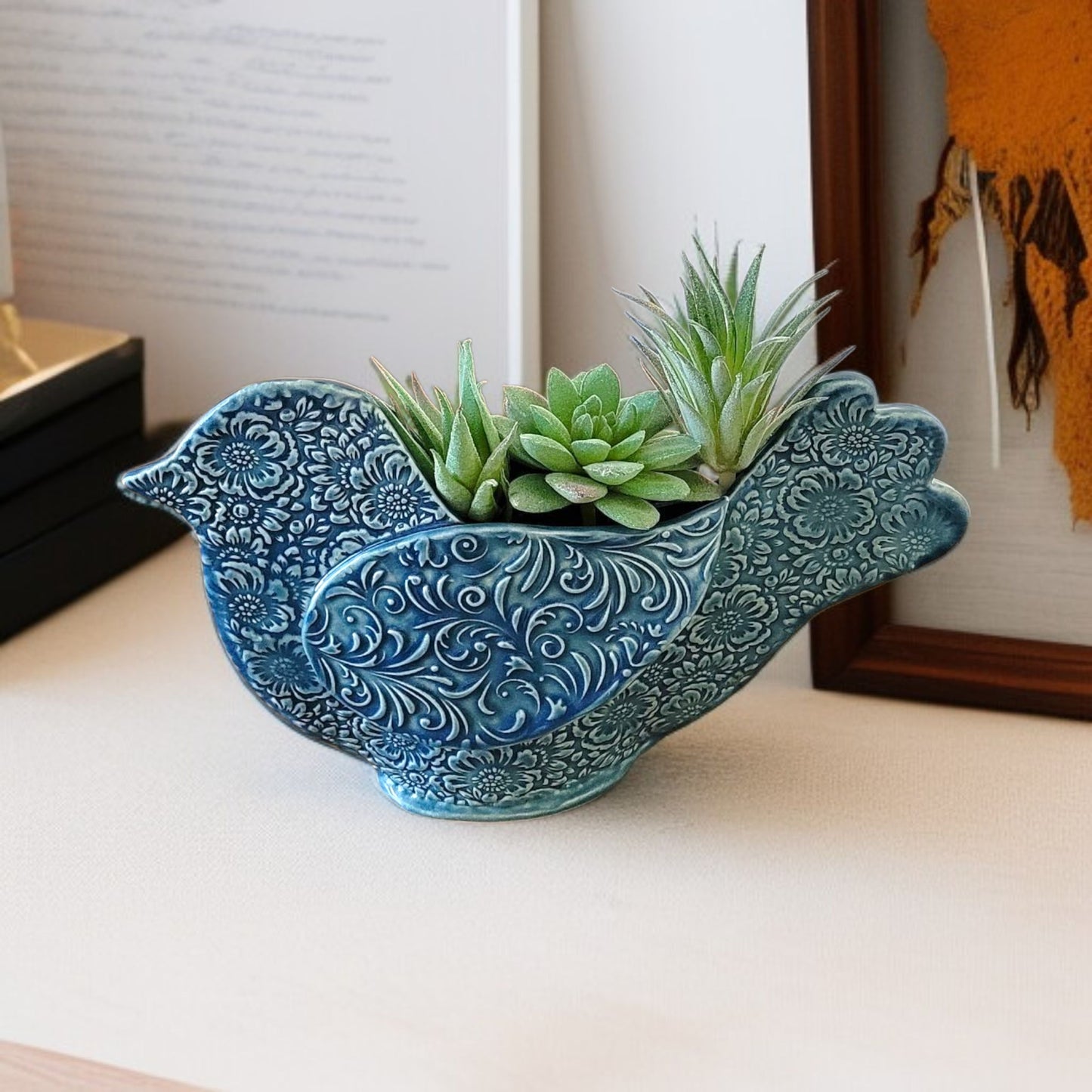 Decorative blue bird-shaped planter with succulents on a light surface.
