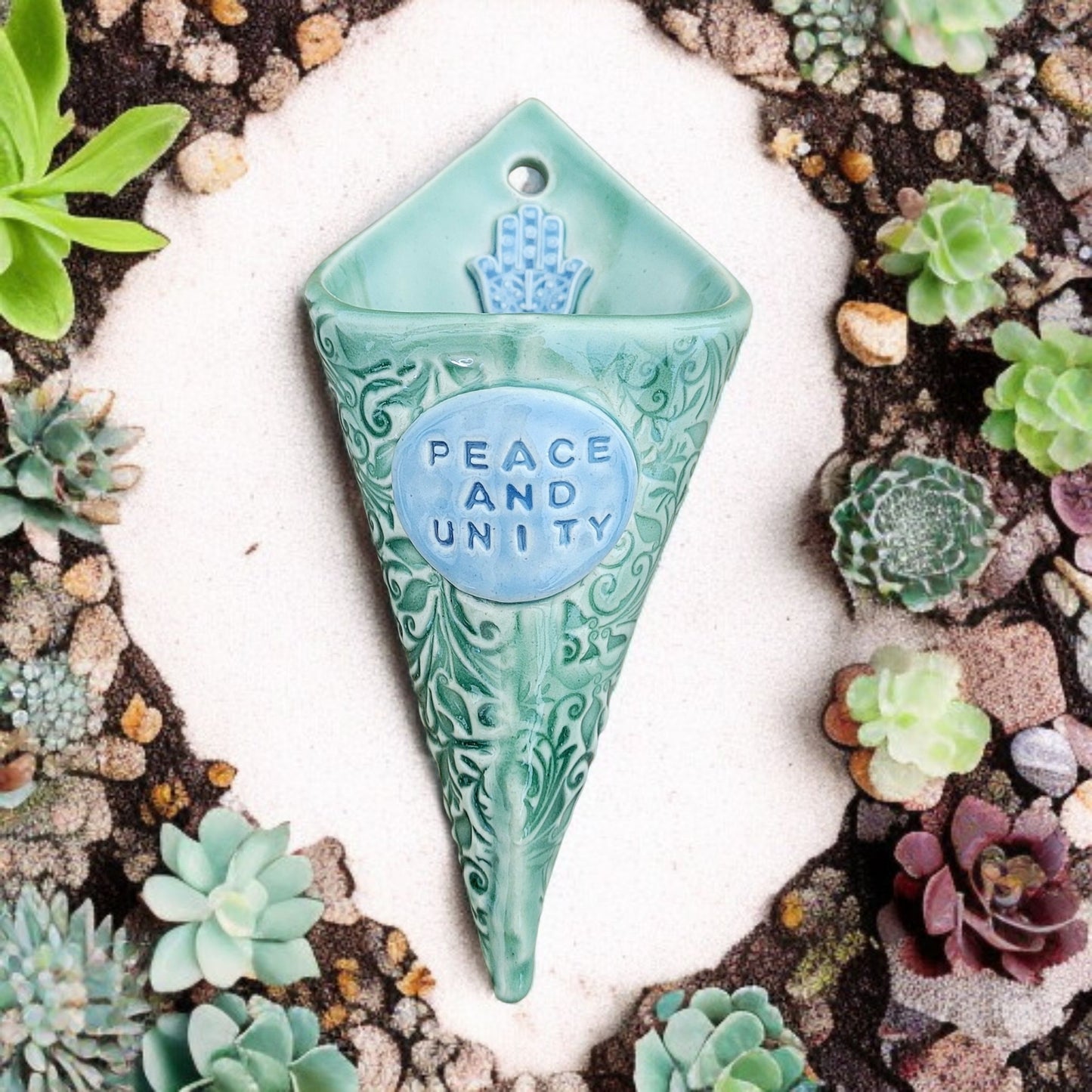 Decorative wall vase with 'Peace and Unity' text surrounded by succulents