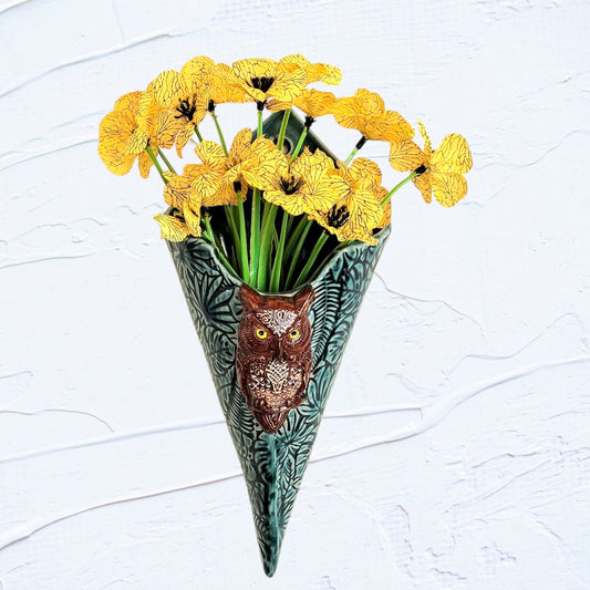 Decorative vase shaped like a cone with an owl design, filled with yellow flowers on a light gray background.