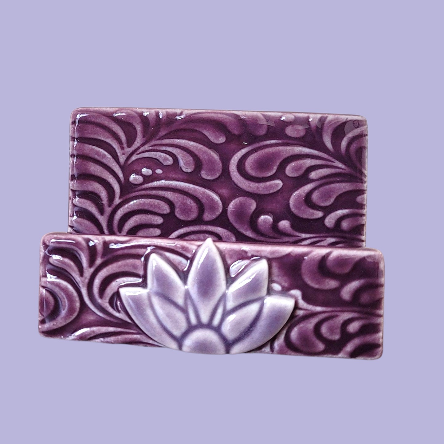 Purple and lavender business card holder with scroll patterns on a light purple background