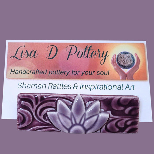 Card with 'Lisa D Pottery' branding sitting in a purple and lavender business card holder.