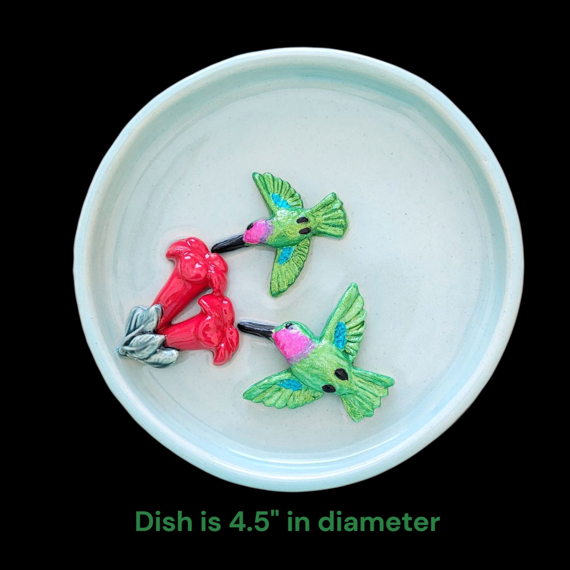 Decorative ceramic blue dish with hummingbirds and flowers on a black background