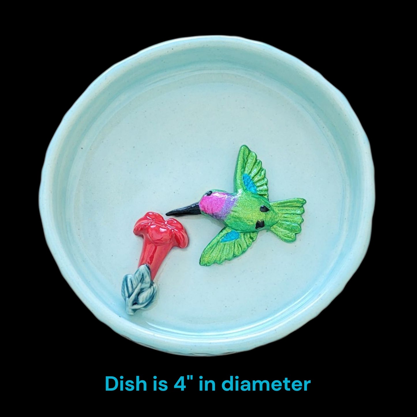 Small blue dish with a decorative hummingbird and flower design on a black background with dish dimension.