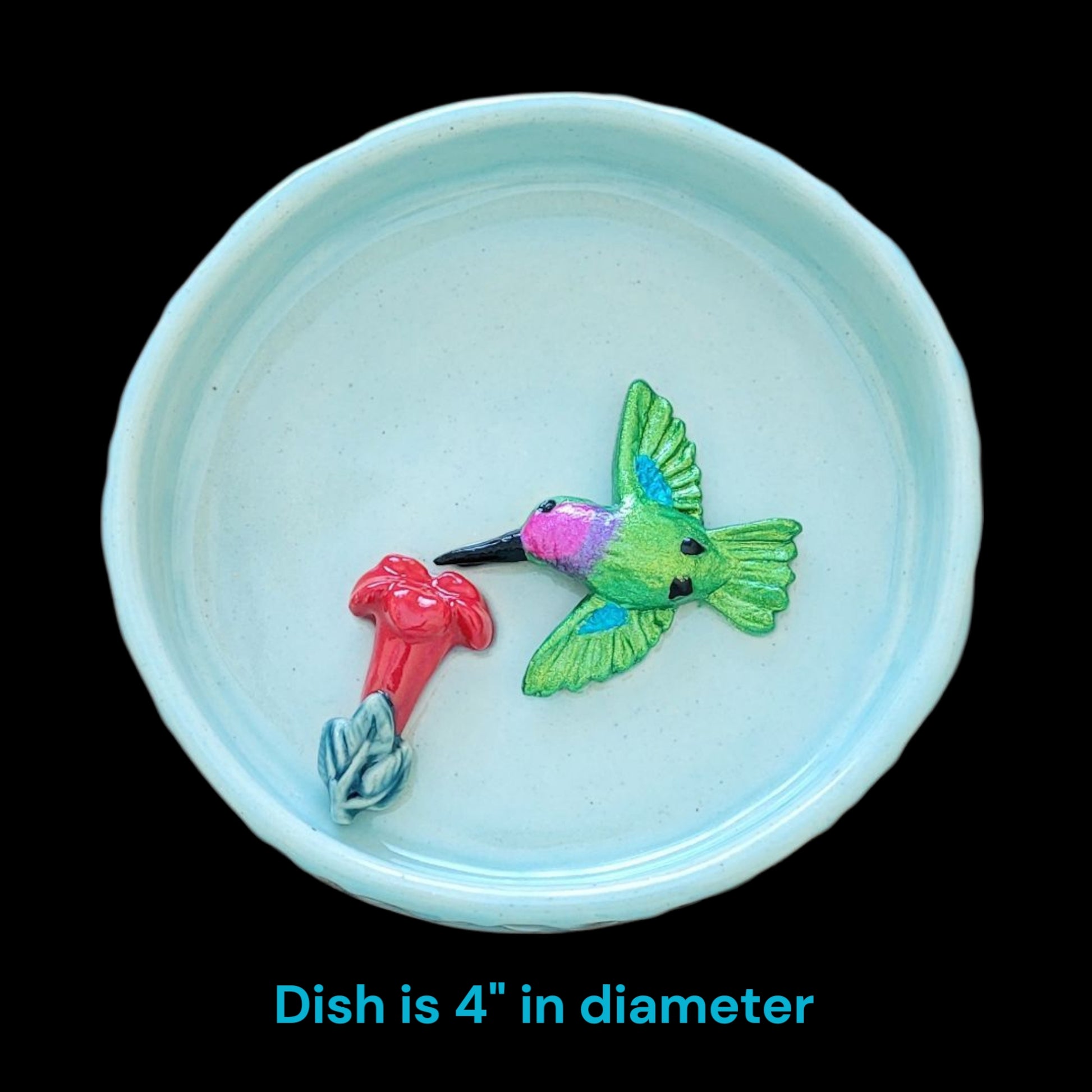Small blue dish with a decorative hummingbird and flower design on a black background with dish dimension.