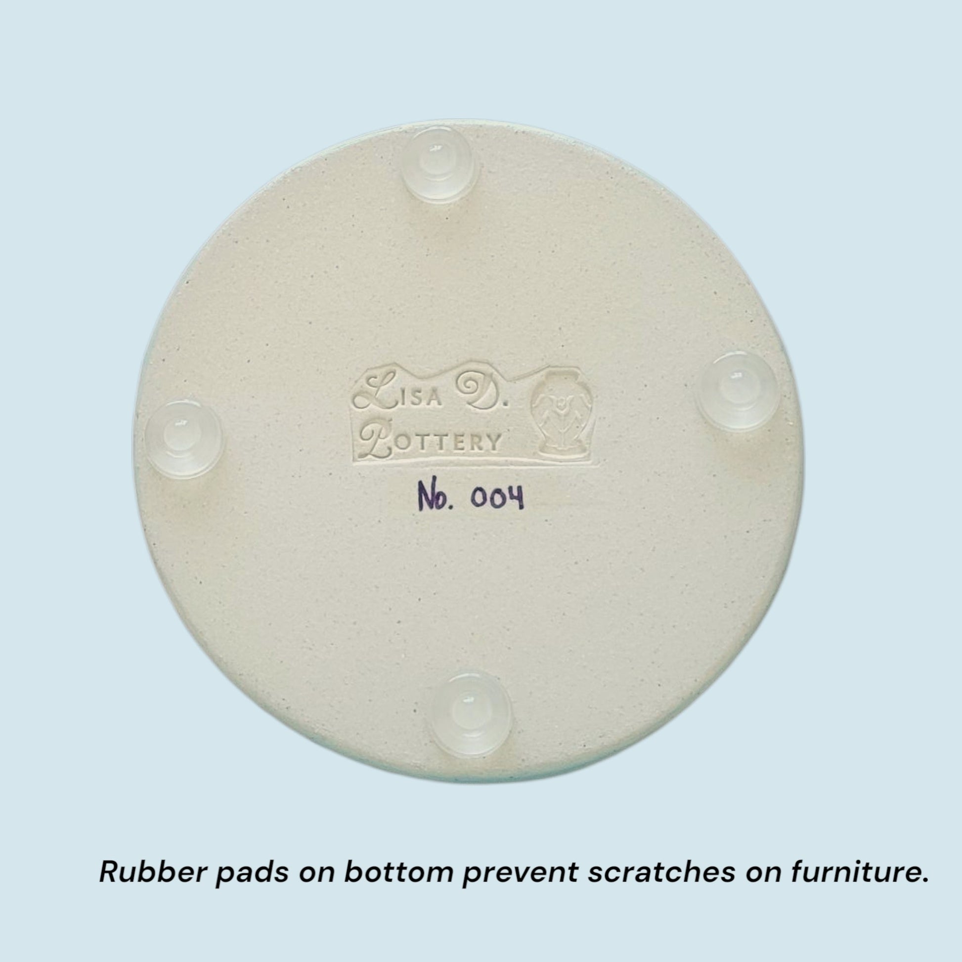 Bottom of trinket dish showing rubber pads and the 'Lisa Pottery' branding on a light blue background
